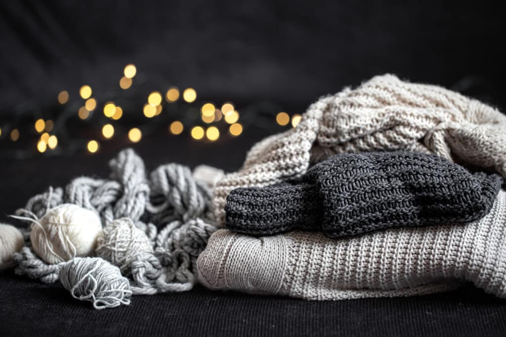 Neatly folded warm jumpers next to bundles of wool, ready for laying up in the cold winter months